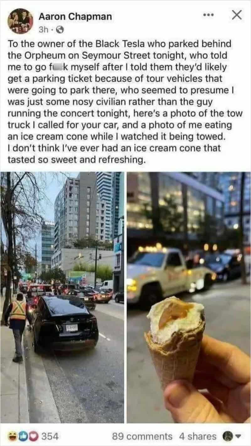A person holds an ice cream cone with a city street and cars in the background.