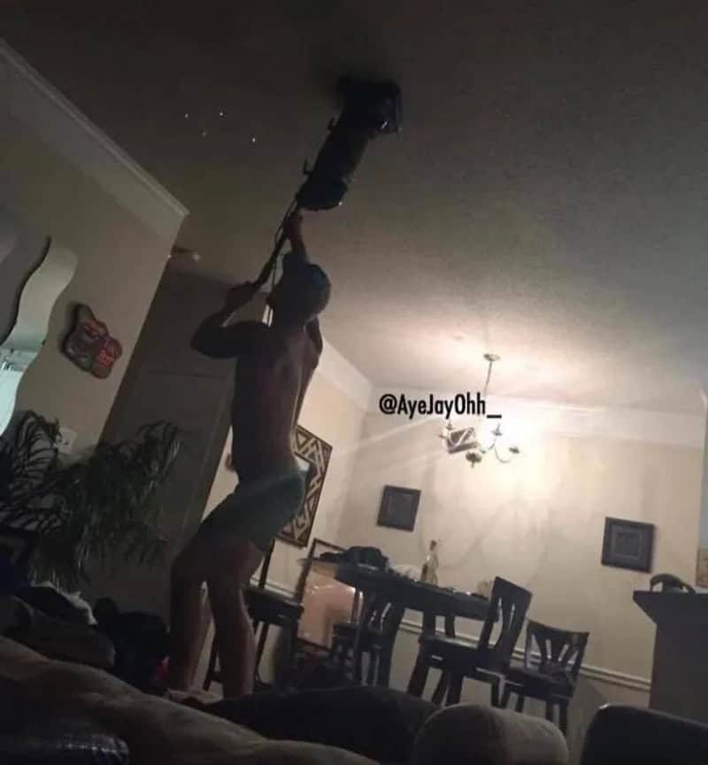 Person hanging from ceiling with a chainsaw, cutting the ceiling.