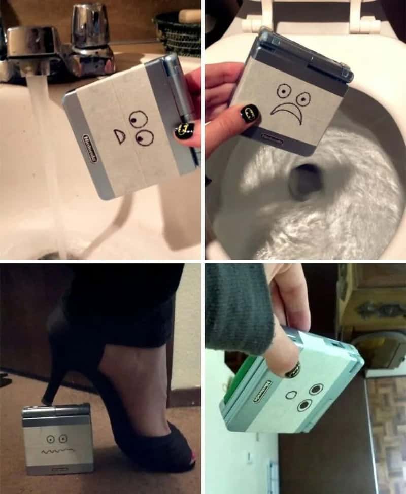 Compact camera with a sad face drawn on it, placed near a sink, toilet, and shoe.