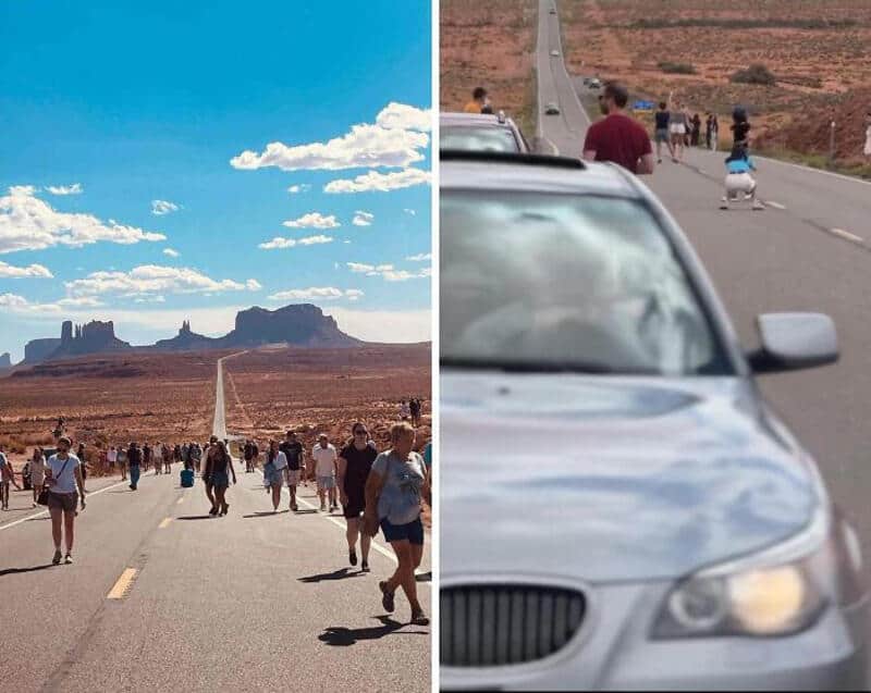 Tourists walking on a road with a desert landscape and rock formations in the background.