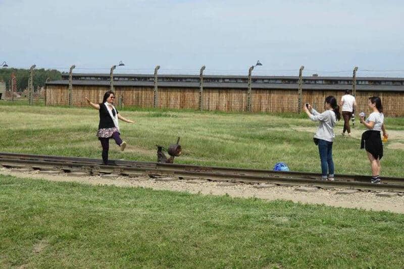 Tourists taking photos near a train track with a dog in the middle.