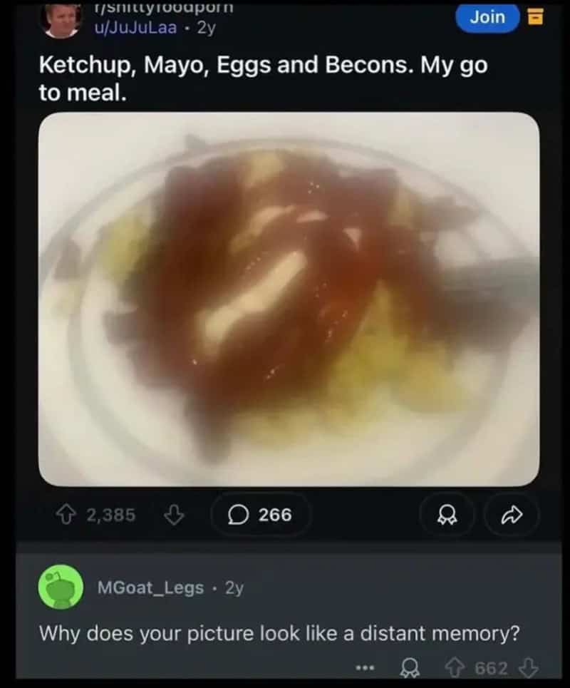 A blurry plate of food with ketchup, mayo, eggs, and beacons, with a fork on the side.
