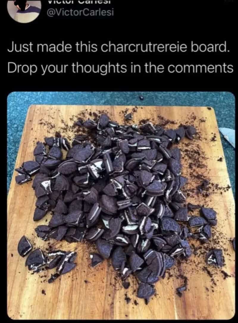 Charcruterie board with broken black chocolate pieces on a wooden cutting board.