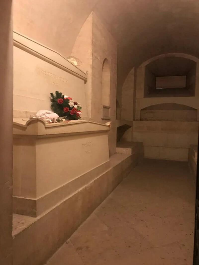 Empty tomb with a bouquet of flowers on the ledge inside a stone chamber.