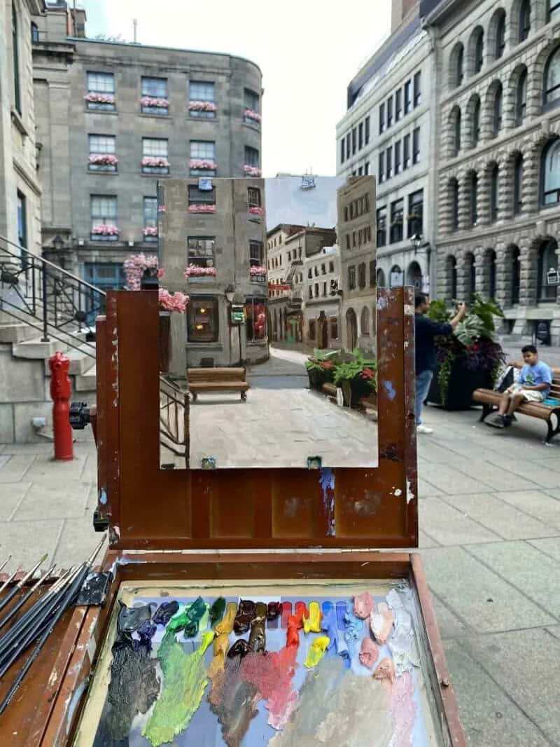 Street artist's palette with various colors and a mirror reflecting city buildings.
