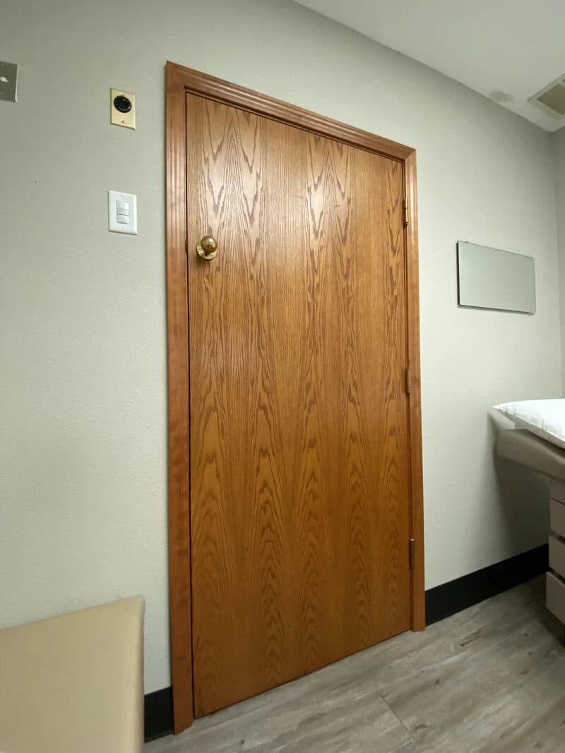 Wooden door with a brass doorknob in a room with light green walls.
