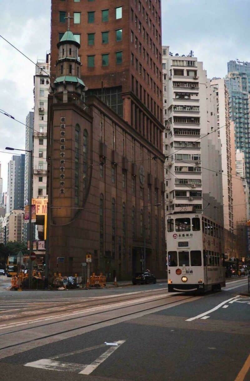 Historic building with a turret and modern skyscrapers in the background, tram on street.
