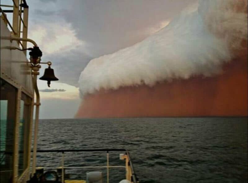 Massive cloud formation over the ocean, resembling a giant wave or landslide.