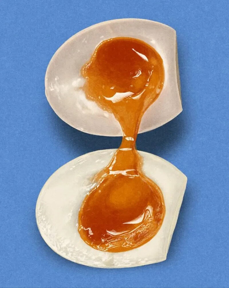 Two broken eggshells with yolk and white on a blue background.