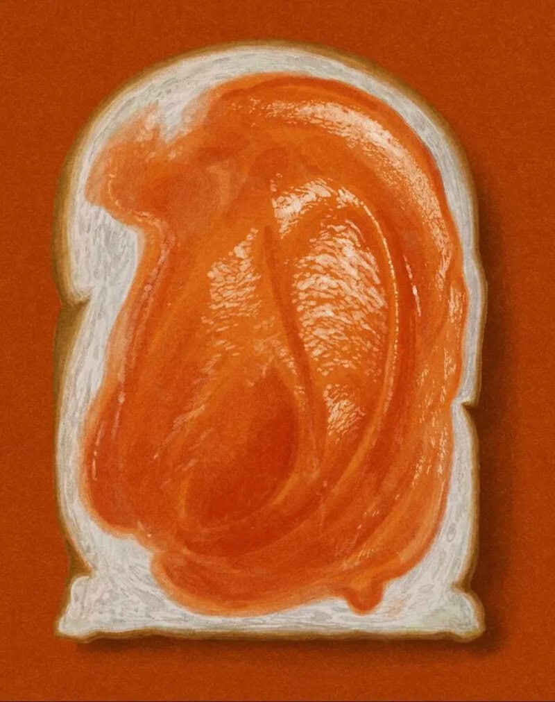 Close-up of a slice of bread with orange-colored spread resembling an ear.