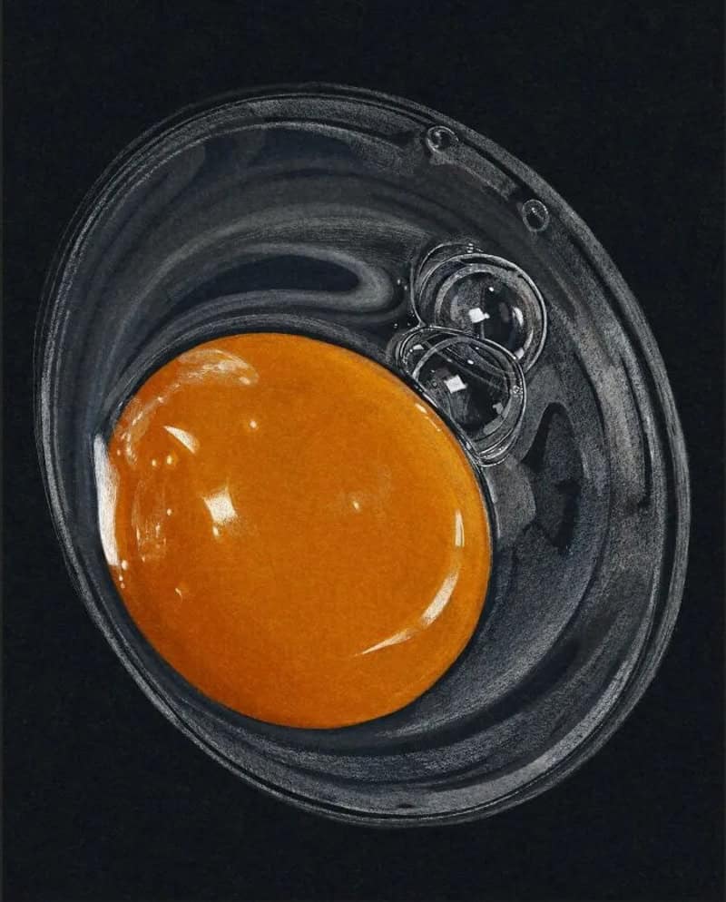 Orange yolk in a clear plastic container on a black background.
