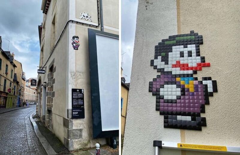 Street art mosaic of a cartoon character on a building wall.