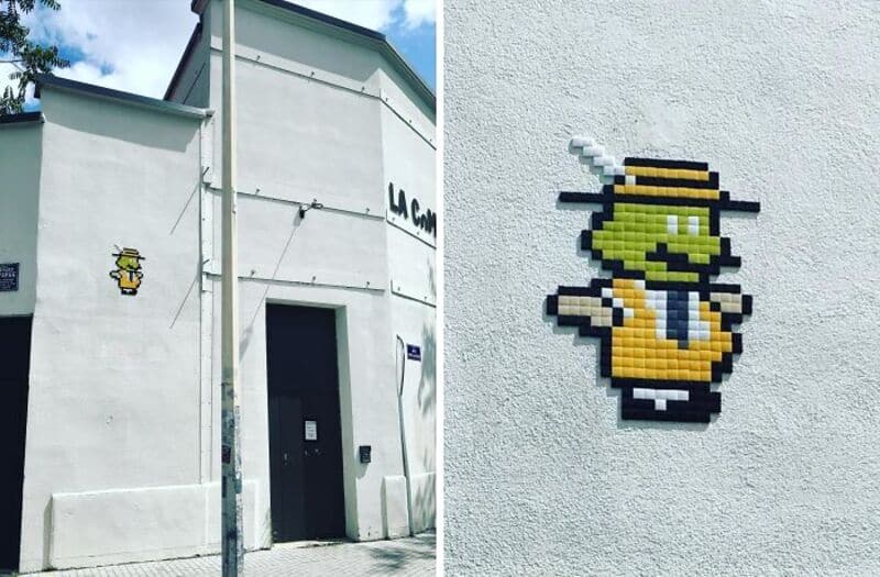Pixel art of a small yellow character with a hat on a white wall.