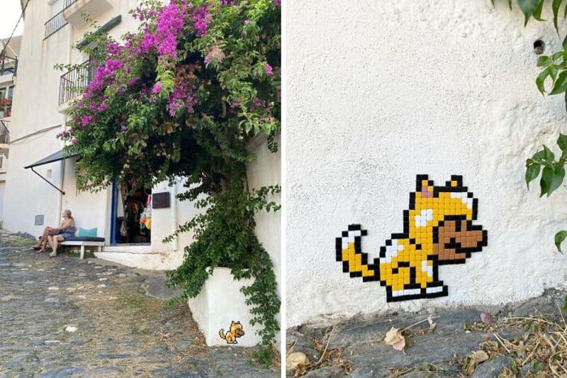 Colorful street art mosaic of a pixelated cat on a white wall.