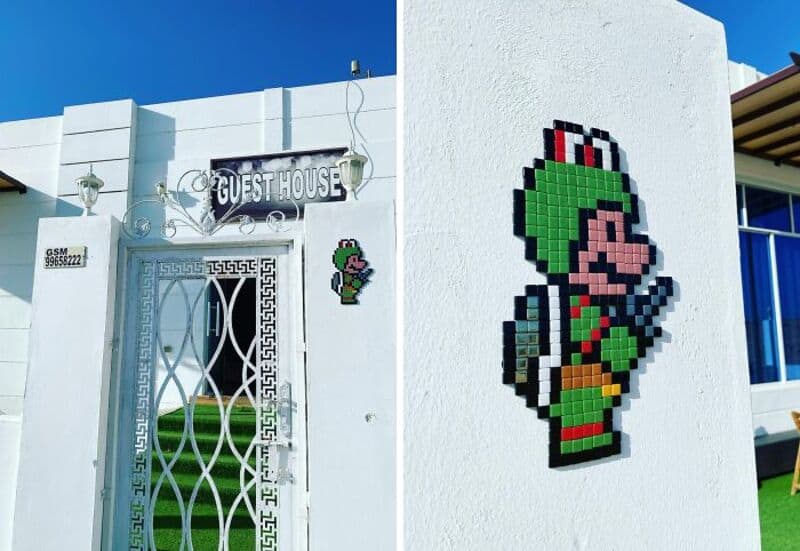 Mario pixel art on white wall near guest house sign in Woup.