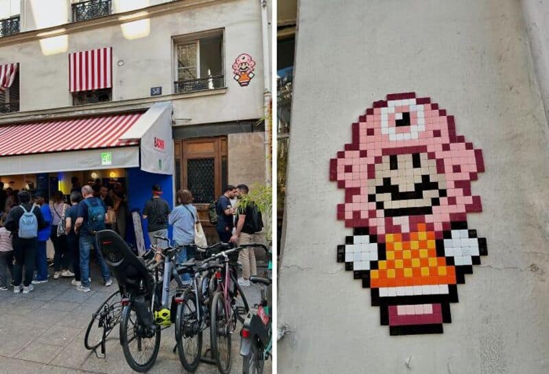 Pixel art of a pink character with a single eye and orange dress on a wall.
