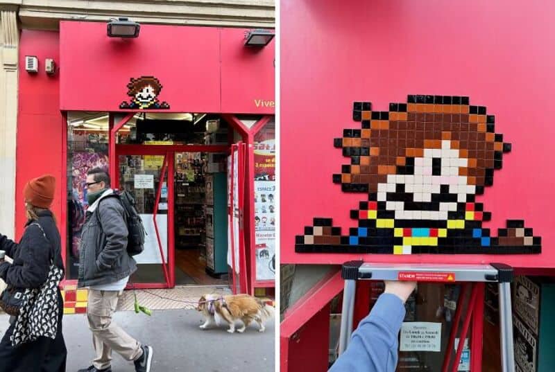 Street art mosaic of a pixelated character on a pink wall outside a store.