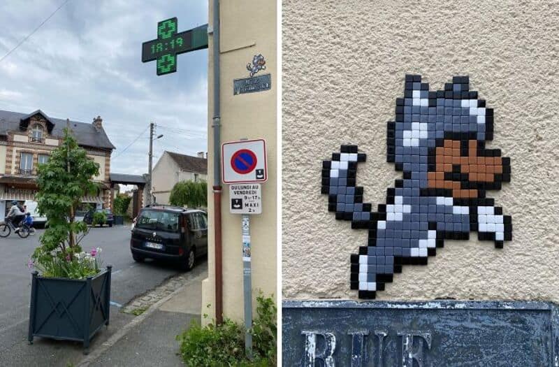 Street scene with a pixel art cat on a wall, street signs, and parked cars.