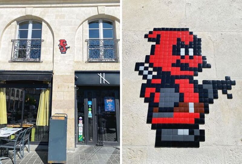 Pixel art of a red character with black and white details on a building wall.