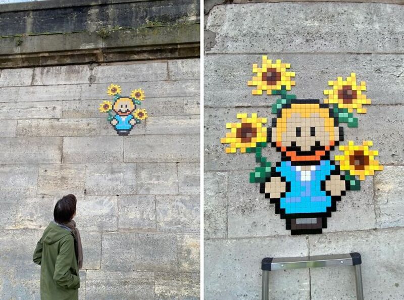 Street art mosaic of a girl with sunflowers on a concrete wall.