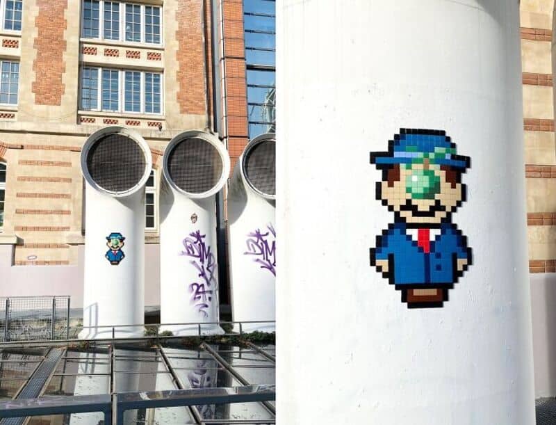 Pixel art of Mario from Super Mario on a white wall in an urban setting.