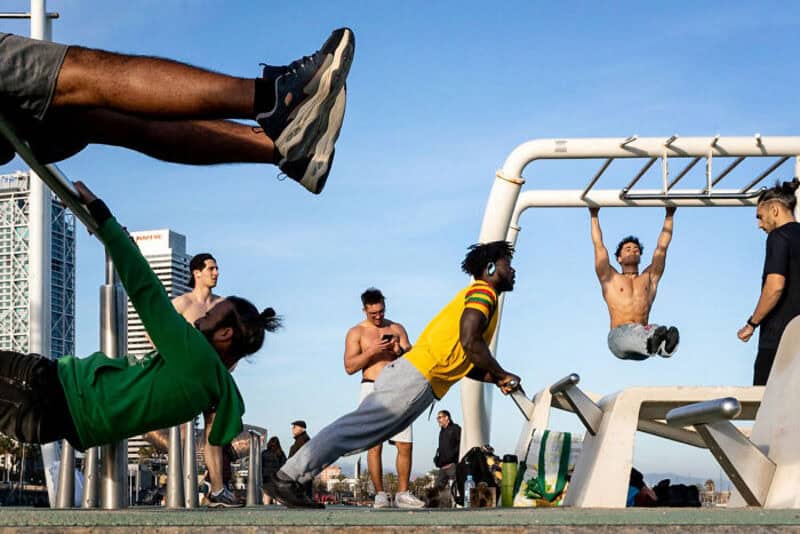 People exercising outdoors on a sunny day with city buildings in the background.