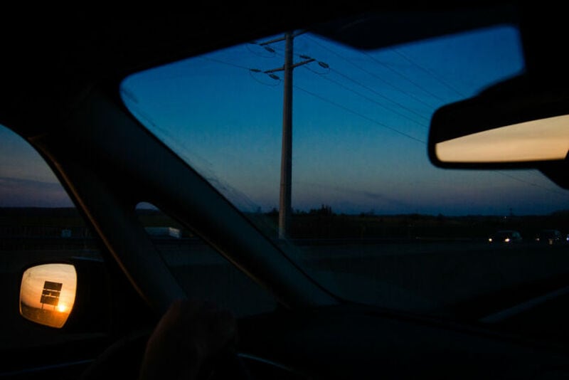 View from inside a car at dusk with power lines and a darkening sky.