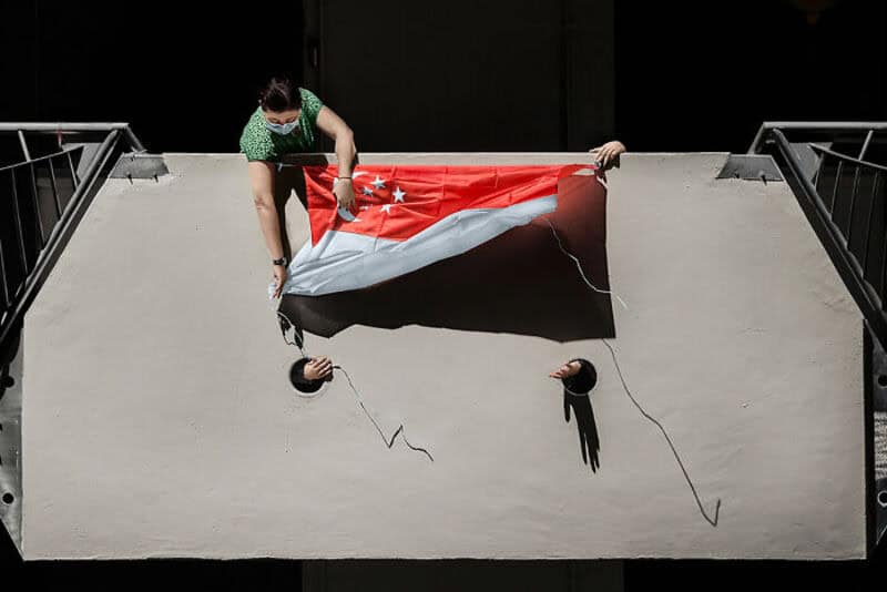 Person hanging a torn flag in a skatepark bowl during a protest.