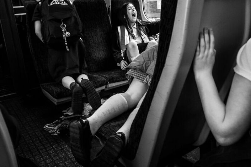 Girl with leg injury sitting on bus seat, another girl with hand on mirror.