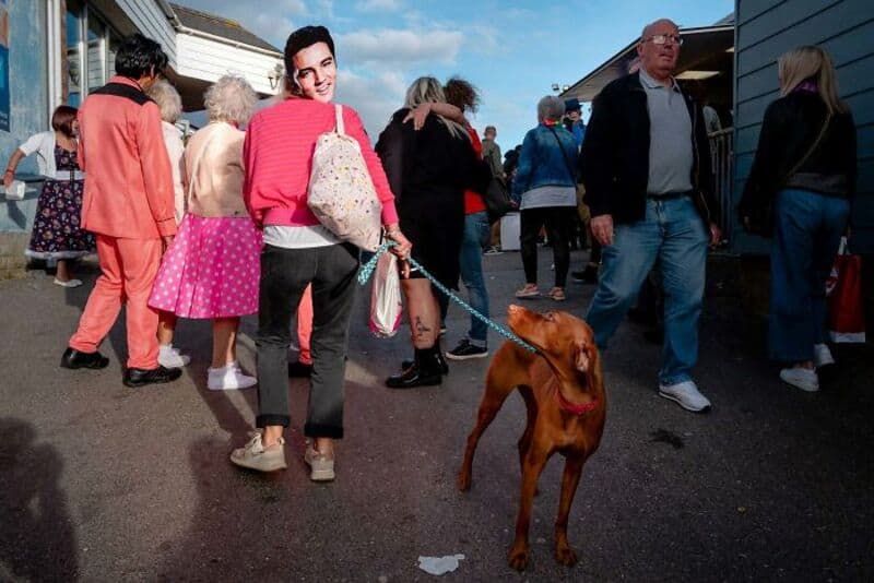 Woman with a dog at a busy outdoor market or event.