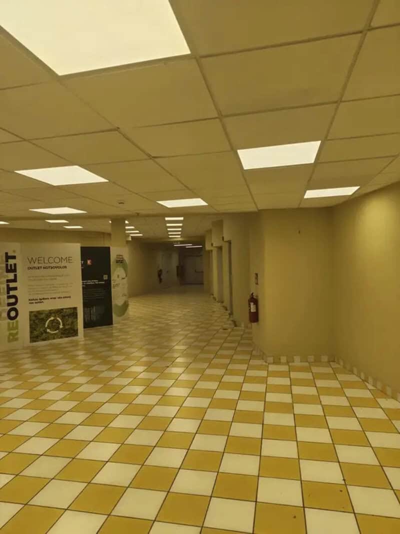 Empty corridor with yellow and white checkered floor and ceiling lights.