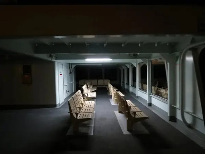 Empty waiting area with rows of benches in a dimly lit space.