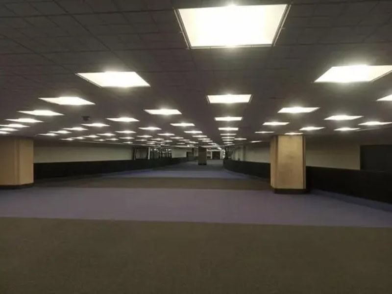 Empty underground parking garage with bright ceiling lights and columns.