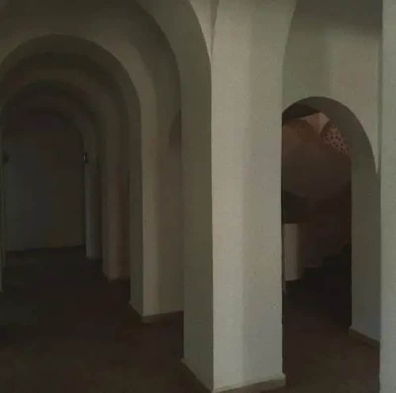 Empty corridor with arched doorways in a dimly lit space.