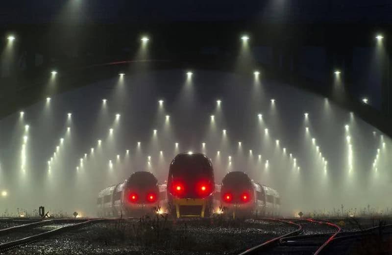 Three trains with glowing red eyes under bright overhead lights in a dark station.