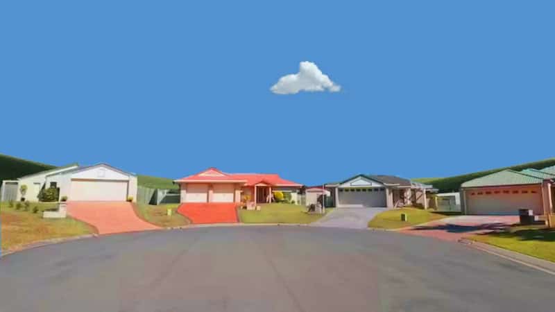 A suburban street with colorful houses under a blue sky with a single cloud.