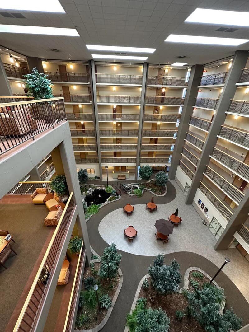 Interior view of a hotel atrium with balconies overlooking a central garden area.