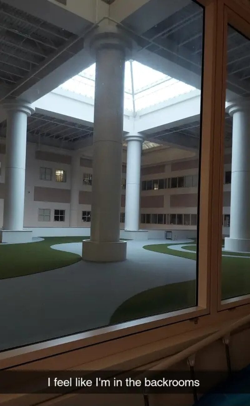 View of a modern building's interior courtyard with large white columns and a glass ceiling.