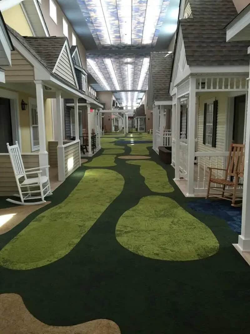 Indoor street with small houses and a winding green and black pathway under a lit ceiling.