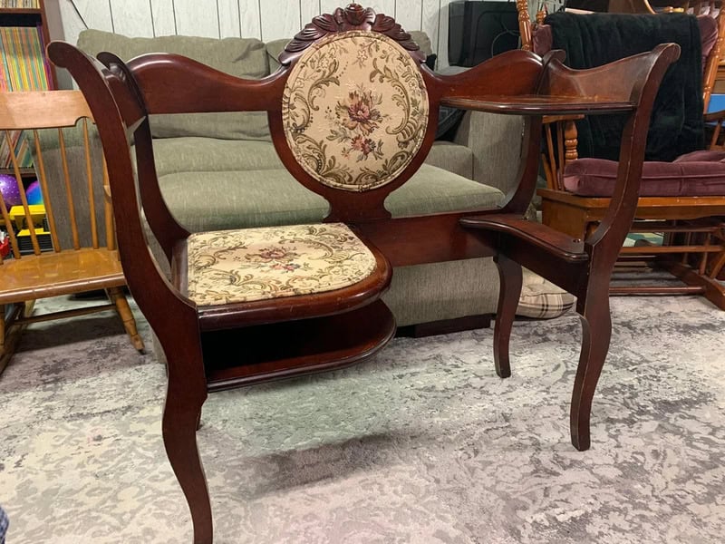 Vintage wooden bench with floral upholstered backrest and seat, in a furniture store.