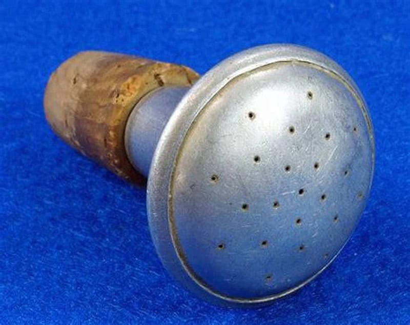 Vintage metal and wood kitchen tool with perforated round head on blue background.