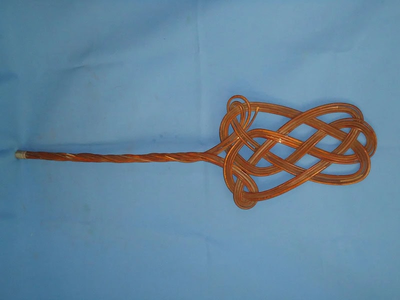 Vintage wooden household item with intricate woven design and long handle.