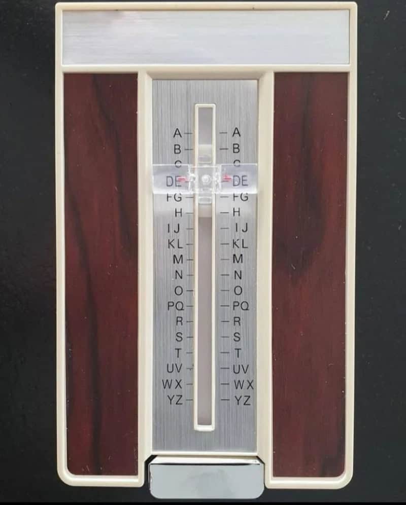 Vintage household thermometer with wooden background and sliding scale.