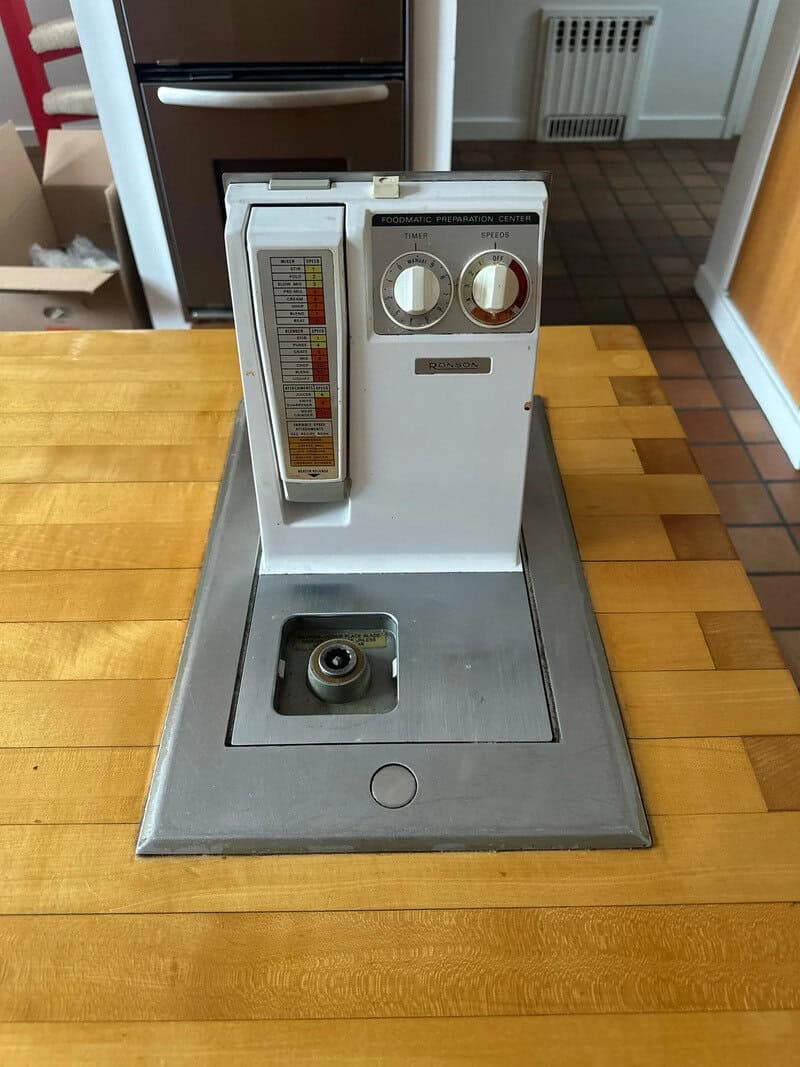 Vintage bread machine with dials and a temperature scale on a wooden table.