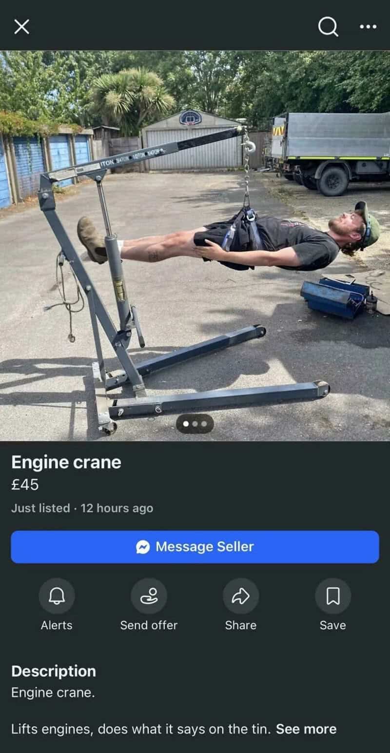 Man lying on a makeshift engine crane with a long arm, outdoors.