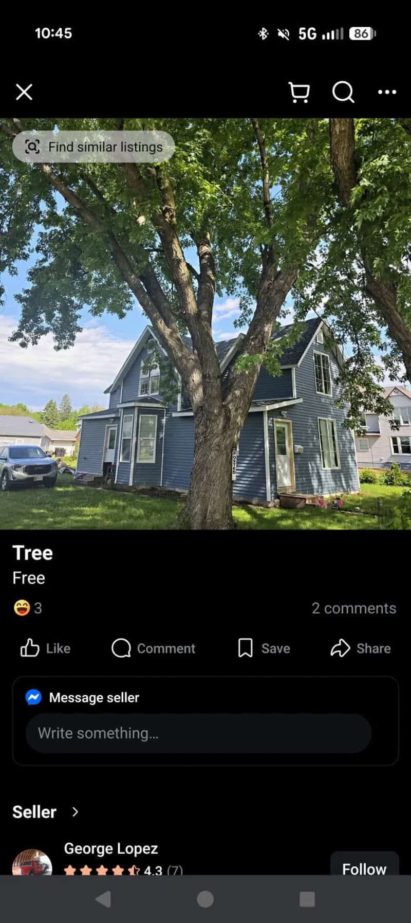 Large tree in front of a blue house on a sunny day.