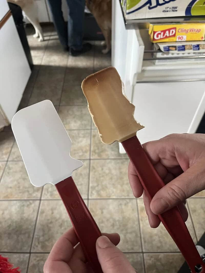 Two ice cream spatulas, one clean and one with ice cream, held in front of a store shelf.