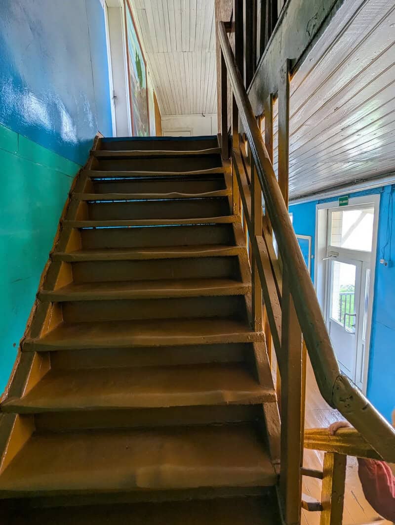 Wooden staircase inside a building with blue and green walls and a window.