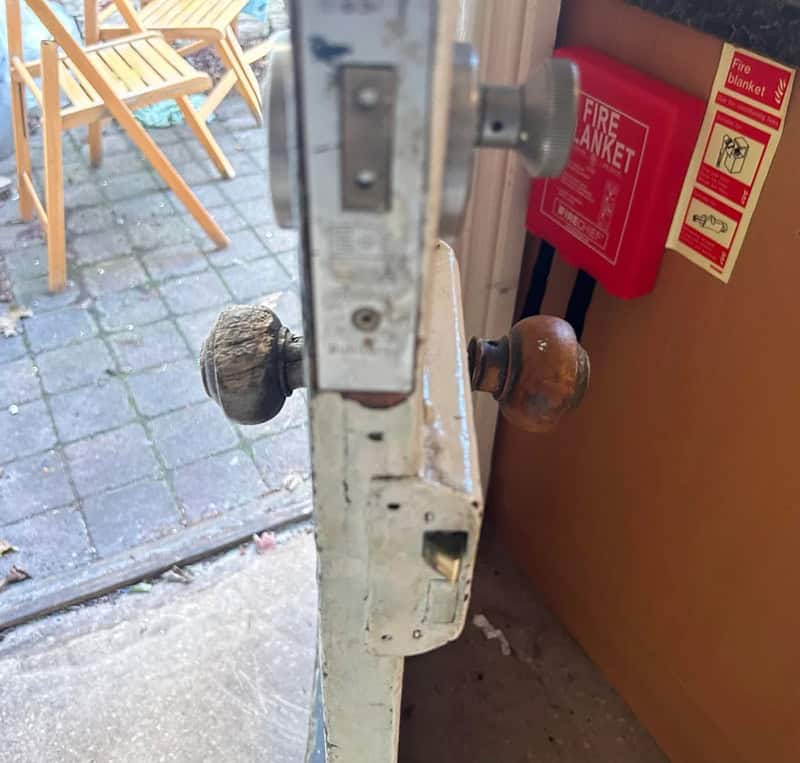 Close-up of an old door latch with two round knobs, one black and one brown.
