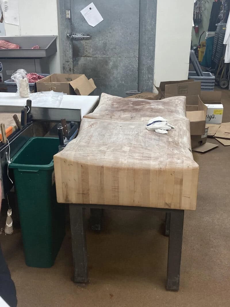 Worn wooden workbench with a cloth on top, in a cluttered workshop.